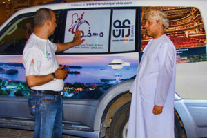 Ali showing Yahya Al Kiyumi the Oman images on the cars 